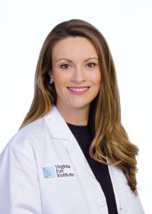 Dr. Nicole Langelier; a caucasian lady in doctors scrubs smiling at the camera in a headshot for virginia eye institute.
